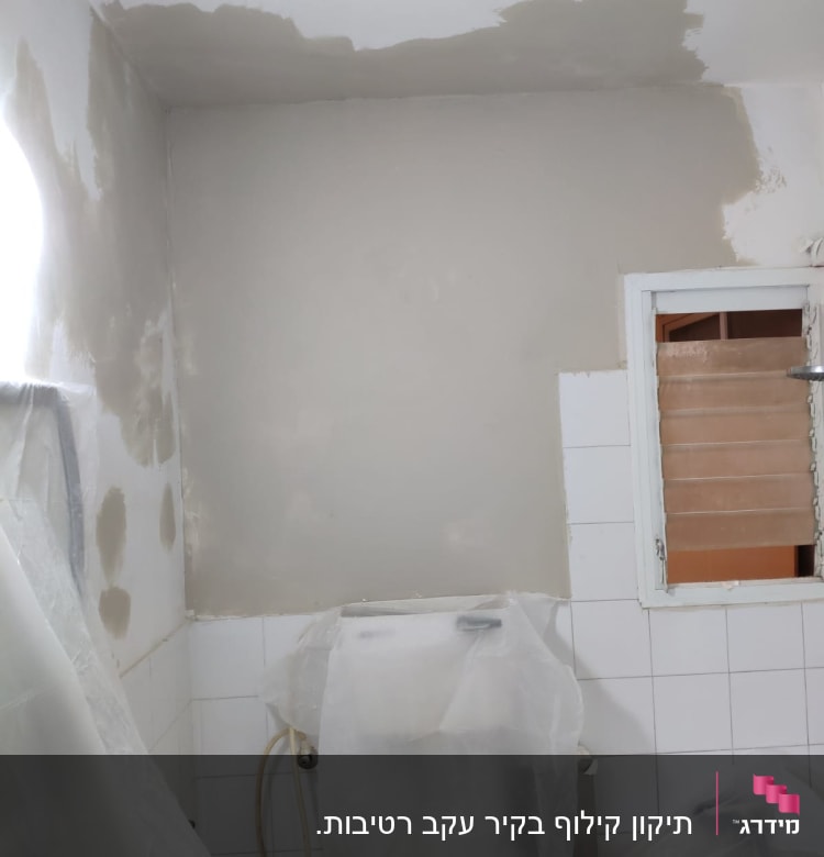 קירות צבועים חלקית בצבע לבן, כיסוי פלסטיק על רהיטים